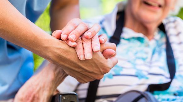 Pflegerin hält die Hand einer Seniorin | Quelle: © Kzenon / Adobe Stock
