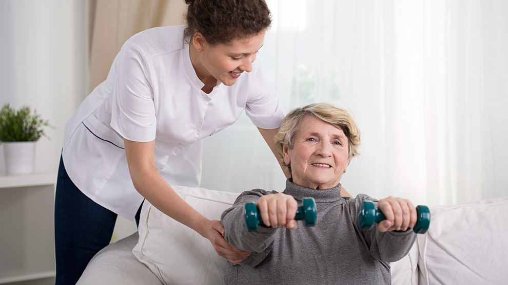 Pflegerin unterstützt ältere Frau bei Sportübungen | Quelle: © Photographee.eu / Adobe Stock