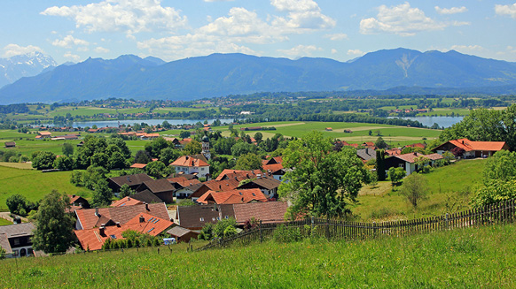 Dorf mit Wiesen und Seen vor Bergen | Quelle: © SusaZoom / Adobe Stock