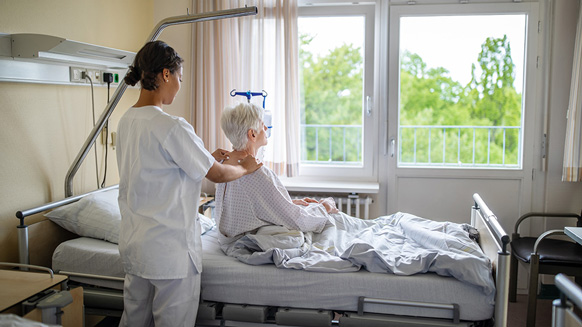 Pflegerin massiert im Krankenhaus ältere Patientin | Quelle: © Luis Alvarez via Getty Images