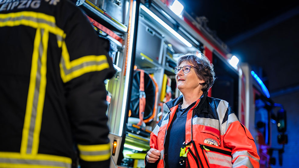 Einsatzkraft des Kriseninterventionsteam Leipzig e.V. im Gespräch mit Feuerwehr | Quelle: © Sächsische Staatskanzlei André Wirsig